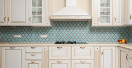 a kitchen with quartz worktops and traditional white wooden kitchen cabinets. There is a white hob chimney placed centrally.