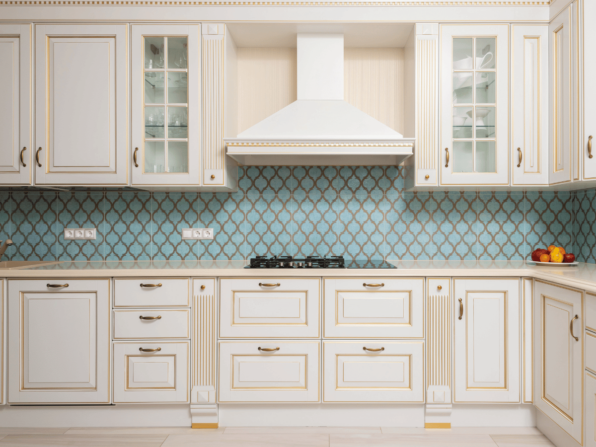 a kitchen with quartz worktops and traditional white wooden kitchen cabinets. There is a white hob chimney placed centrally.