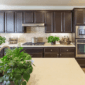 a modern kitchen refit with dark painted cabinets and a light quartz worktop. There are several green plants on the surfaces.